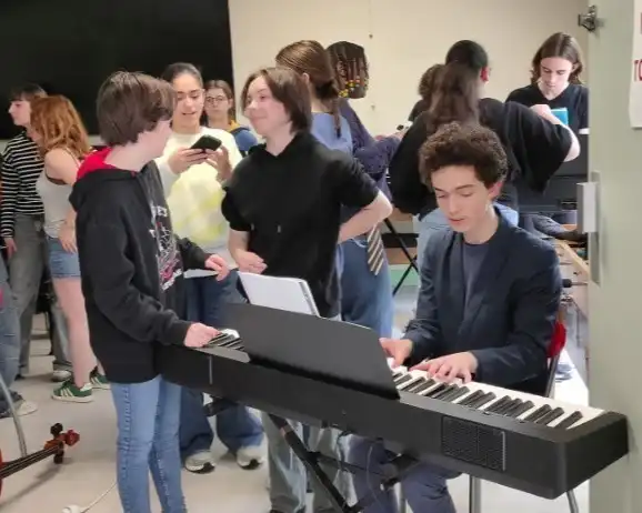 Un groupe d'élève font des essais avec un piano.