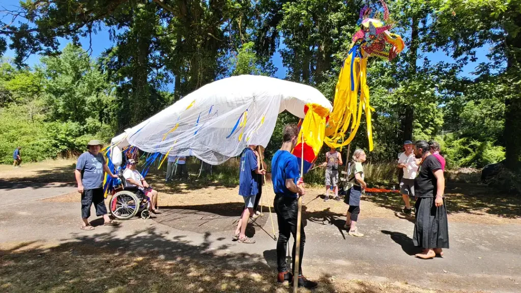 La grande marionnette représantant un dragon déambule dans la cour du Foyer de la Clairière.
