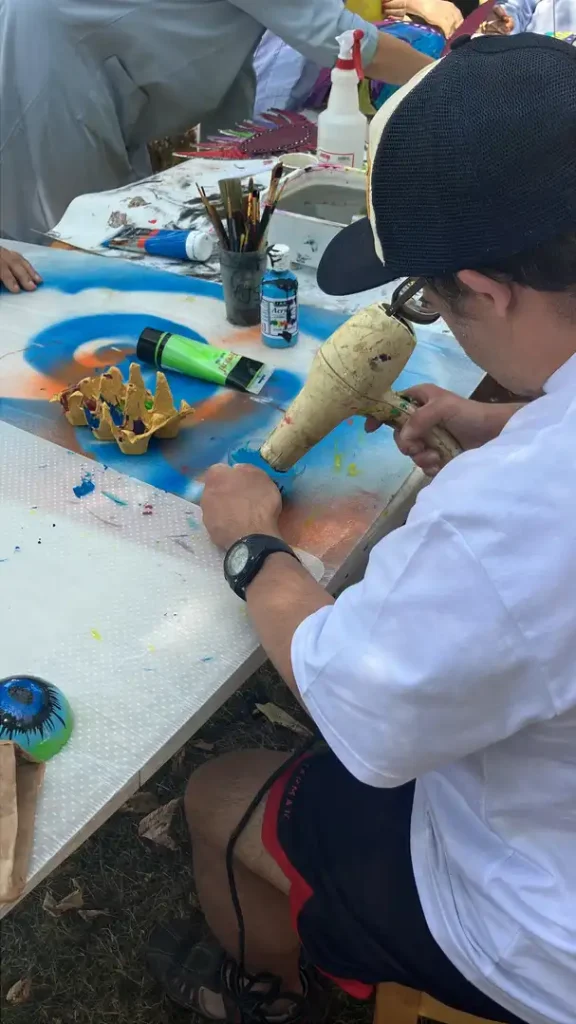 Une personne accompagné fait sécher la peinture à l'aide d'un sèche cheveux.
