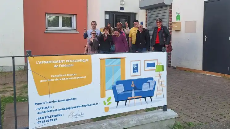 Un groupe pose devant la bandore du dispositif "L'Apartement pédagogique de l'Aidaphi".