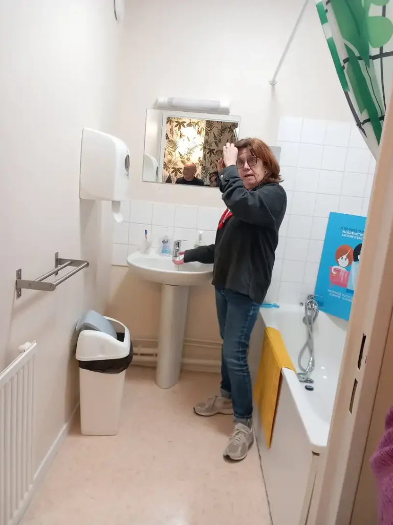 Dans une salle de bain adapté, on peut voir une personne faire couler de l'eau dans le but de se laver la main.