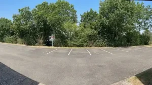 Image du parking en plan large, l'équipe des espaces verts ont entretenus les arbres et les plantes.
