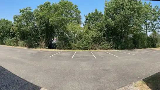 Image du parking en plan large, l'équipe des espaces verts ont entretenus les arbres et les plantes.